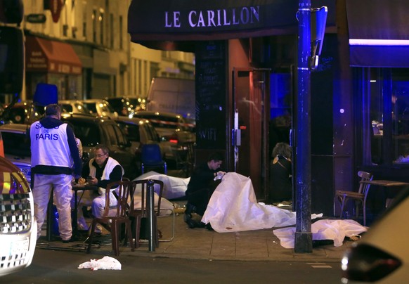 Victims lay on the pavement in a Paris restaurant, Friday, Nov. 13, 2015. Police officials in France on Friday reported a shootout in a Paris restaurant and an explosion in a bar near a Paris stadium. ...
