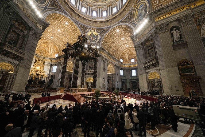 People look at the body of late Pope Emeritus Benedict XVI laid out in state inside St. Peter's Basilica at The Vatican, Monday, Jan. 2, 2023. Benedict XVI, the German theologian who will be reme ...