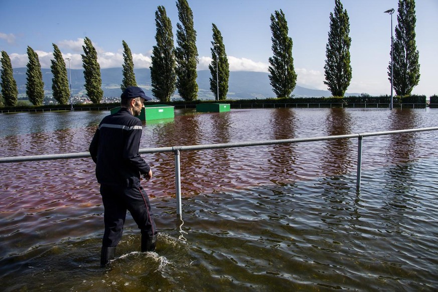 Un pompier observe l&#039;eau du lac deborde sur un terrain d&#039;athletisme lors de la montee de l&#039;eau du lac de Neuchatel suite aux fortes precipitations des derniers jours le dimanche 18 juil ...