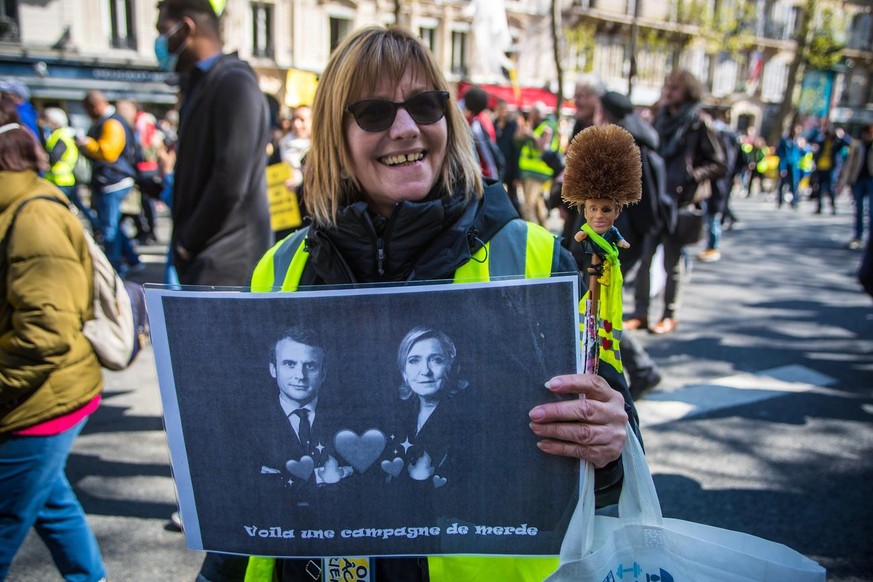 epa09880394 A protester shows a poster displaying Marine Le Pen and French President Emmanuel Macron depicted as newlyweds during a Climate March demonstration against global warming, in Paris, France ...