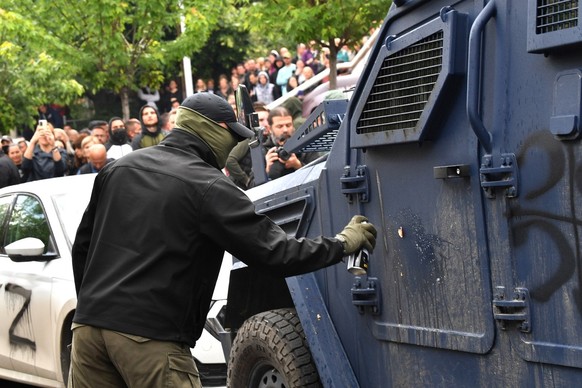 epa10661634 A protester spray paints a Kosovo special police vehicle in front of the building of the municipality in Zvecan, Kosovo, 29 May 2023. At least ten people were injured in violence between K ...