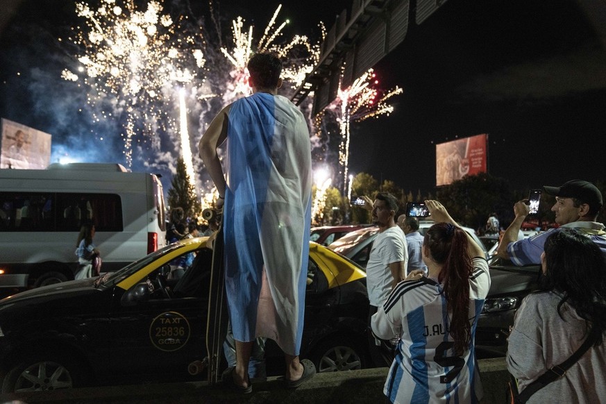 Soccer fans watch fireworks welcoming home the players from the Argentine soccer team that won the World Cup after they landed at Ezeiza airport on the outskirts of Buenos Aires, Argentina, Tuesday, D ...