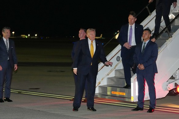 As Defense Secretary Pete Hegseth watches at left, President Donald Trump gestures as he switches planes at U.S. Air Force Base, RAF Mildenhall in Suffolk Eastern England, on his way back to Washingto ...