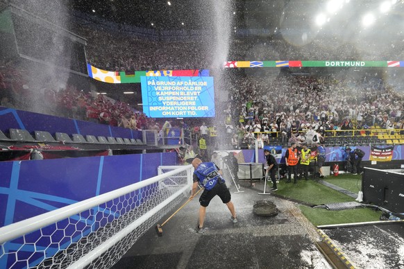 Stadium staff sweep water on the sidelines during a round of sixteen match between Germany and Denmark at the Euro 2024 soccer tournament in Dortmund, Germany, Saturday, June 29, 2024. (AP Photo/Darko ...