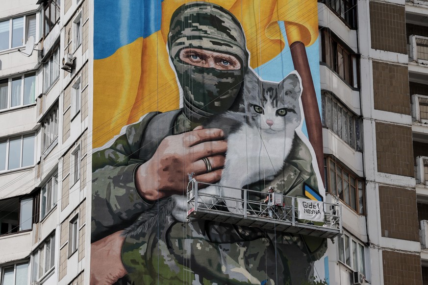 epa10896888 Artist Olena Noyna (L) works on a mural depicting a Ukrainian serviceman holding a cat, on a building in Kyiv, Ukraine, 03 October 2023, amid the Russian invasion. EPA/Oleg Petrasyuk