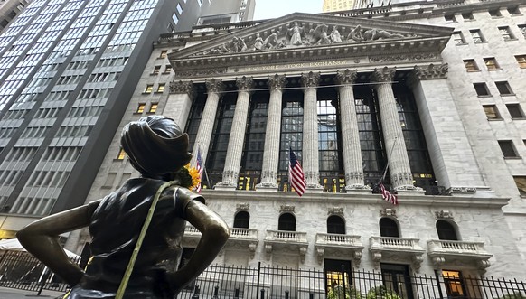 FILE - The Fearless Girl statue, with a flower draped on the shoulder, stands outside the New York Stock Exchange on Oct. 23, 2024. (AP Photo/Peter Morgan, File)