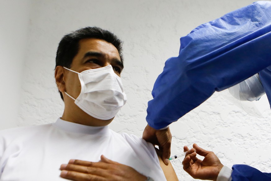 epa09057075 A handout photo made available by Miraflores press shows the President of Venezuela Nicolas Maduro (L) while he is vaccinated against the coronavirus in Caracas, Venezuela, 06 March 2021.  ...