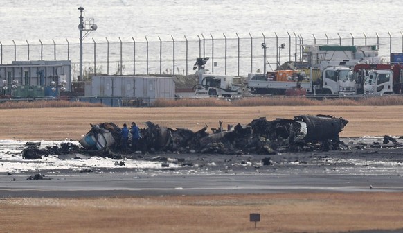 epa11054538 Tokyo Metropolitan Police investigators inspect the area around the Japan Coast Guard aircraft that collided with a Japan Airlines passenger plane at Haneda Airport in Tokyo, Japan, 03 Jan ...