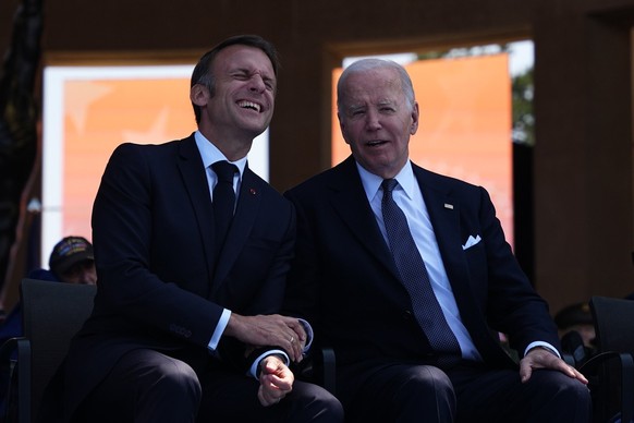 epa11393147 President Joe Biden and French President Emmanuel Macron laugh during a commemorative ceremony to mark D-Day 80th anniversary, Thursday, June 6, 2024 at the US cemetery in Colleville-sur-M ...