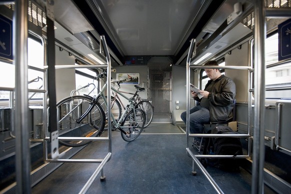 A man sits in a bicycle carriage of an InterCity train of the Swiss Federal Railways SBB from Berne to Biel, Switzerland, and reads a magazine, on November 27, 2009. (KEYSTONE/Gaetan Bally) 

Ein Mann ...