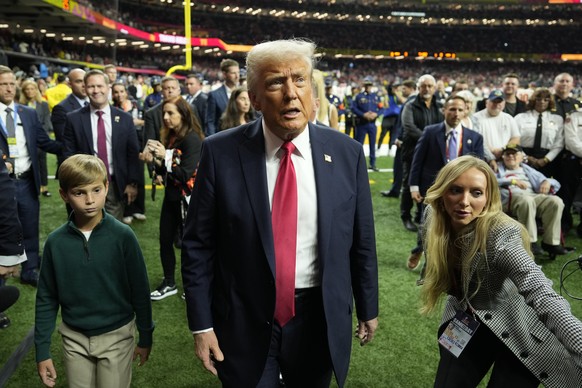 President Donald Trump, center, with his grandson Theodore, left walks on the field before the start of the NFL Super Bowl 59 football game between the Philadelphia Eagles and the Kansas City Chiefs,  ...