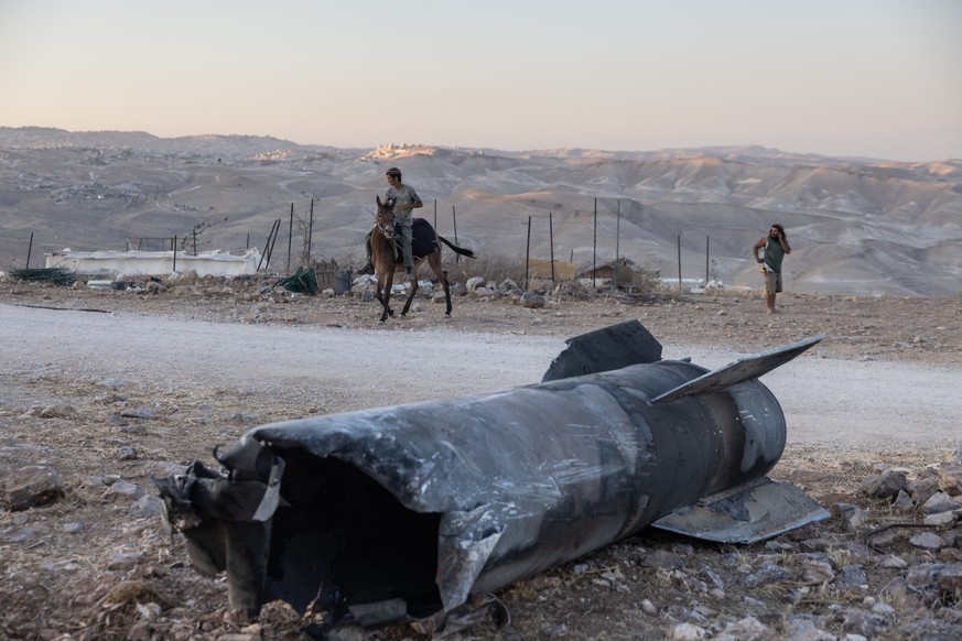 A man rides a horse next to the remains of an Iranian missile that fell at an outpost near the Israeli settlement of Tekoa in the occupied West Bank, on 29 June 2025, in the aftermath of the 12-day wa ...