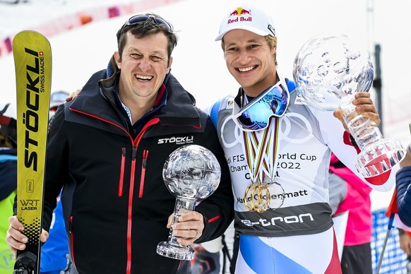 Marco Odermatt of Switzerland poses with the men&#039;s overall crystal globe trophy and his servicman Chris Loedler after the podium ceremony at the FIS Alpine Skiing World Cup finals in Meribel, Fra ...