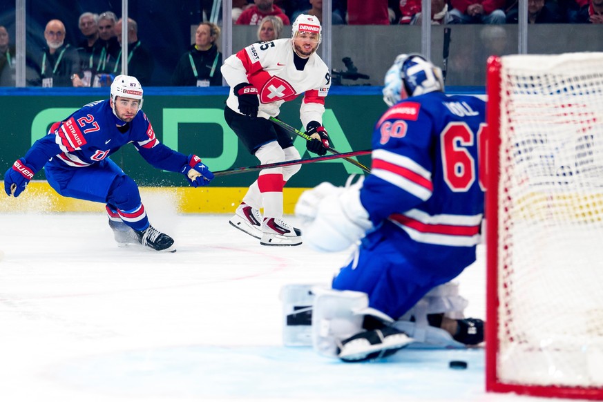 Switzerland's Sven Andrighetto, center, scores the team's second goal past United States goaltender Joseph Woll, during a Group A preliminary round game between United States and Switzerland ...