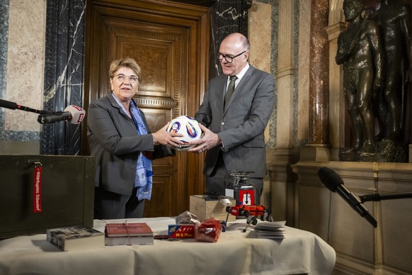 Bundesraetin Viola Amherd, links, uebergibt ihrem Nachfolger als VBS Departementschef, Bundesrat Martin Pfister, verschiedene Geschenke im Zusammenhang mit dem Departement, hier einen Fussball, am Fre ...