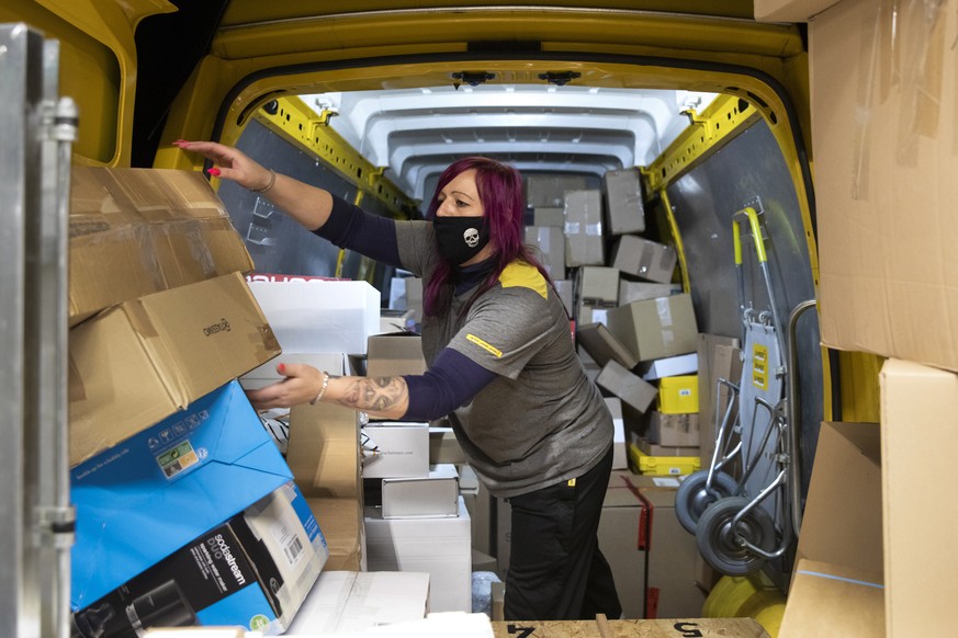 Die Paketbotin Leila Meyer fuellt am fruehen Morgen einen Lieferbus der Post mit Paketen, im Paketzentrum Haerkingen, am Mittwoch, 9. Dezember 2020, in Haerkingen. (KEYSTONE/Peter Klaunzer)