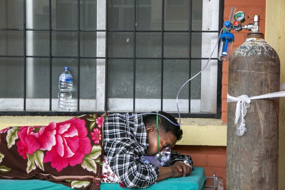 A COVID-19 patient receives oxygen as he lies on a bed outside an emergency ward of a government run hospital in Kathmandu, Nepal, Friday, May 7, 2021. Across the border from a devastating surge in In ...