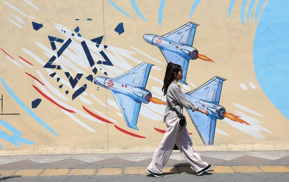 epa13023951 An Iranian girl walks past an anti-Israeli mural on a street in Tehran, Iran, 08 June 2026. Iran and Israel exchanged fire after Iran launched missiles at Israel in retaliation for an earl ...