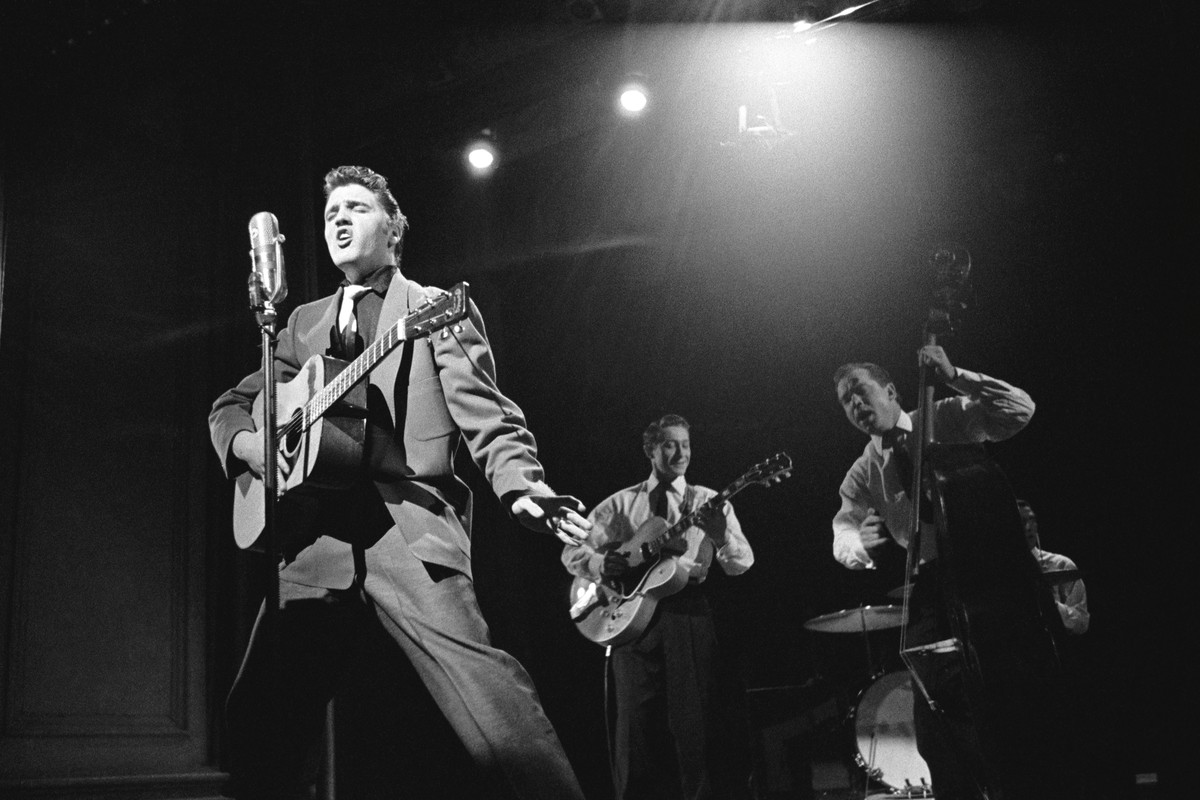 This March 17, 1956 photo provided by courtesy of Taschen shows, Elvis Presley, left, and band members, Scotty Moore, on guitar, Bill Black on bass, and DJ Fontana on drums, during a live performance  ...