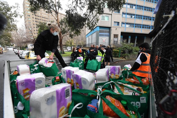 epa08531566 People unload food and provisions from the back of a ute which will be distributed by firefighters throughout a public housing tower in North Melbourne, Australia, 07 July 2020. Nine tower ...