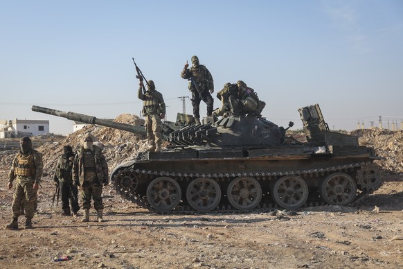 Syrian opposition fighters stand atop a seized Syrian army armoured vehicle in the outskirts of Hama, Syria, Tuesday Dec. 3, 2024. (AP Photo/Ghaith Alsayed)