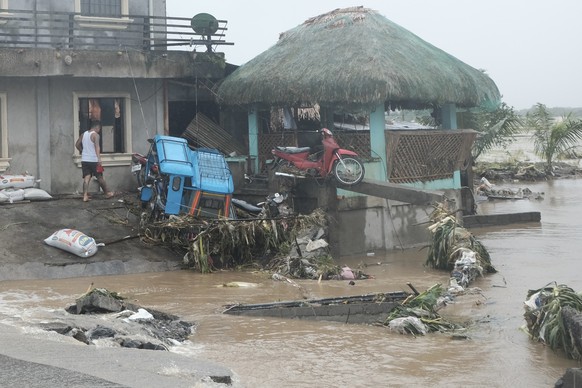 A man walks past damages caused by flash floods on Thursday Oct. 24, 2024 after Tropical Storm Trami, locally named Kristine, dumped heavy rains at Libon town, Albay province, Philippines. (AP Photo/J ...