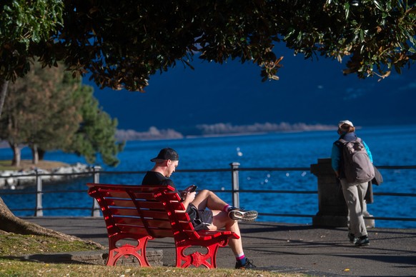 Menschen geniessen an der Seepromenade am Lago Maggiore in Locarno die warmen Temperaturen, aufgenommen am Samstag, 23. Dezember 2023. (KEYSTONE/Ti-Press/Samuel Golay)