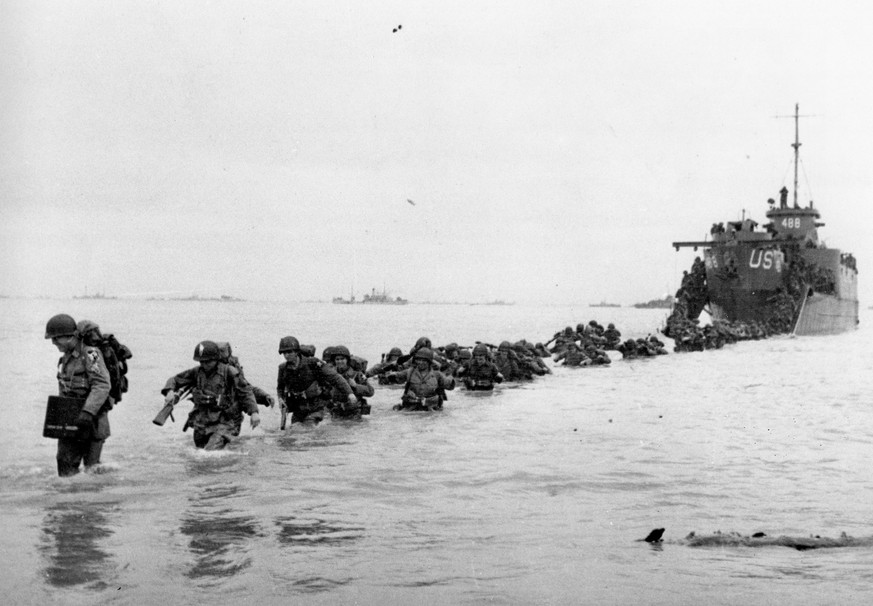 FILE - U.S. reinforcements wade through the surf from a landing craft in the days following D-Day and the Allied invasion of Nazi-occupied France at Normandy in June 1944 during World War II. On D-Day ...