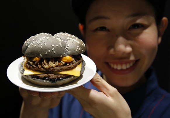 An employee of McDonald&#039;s Japan poses with the Ikasumi (squid ink) burger at one of its fast-food outlets in Tokyo October 8, 2014. McDonald&#039;s Japan has launched the Halloween-themed black b ...