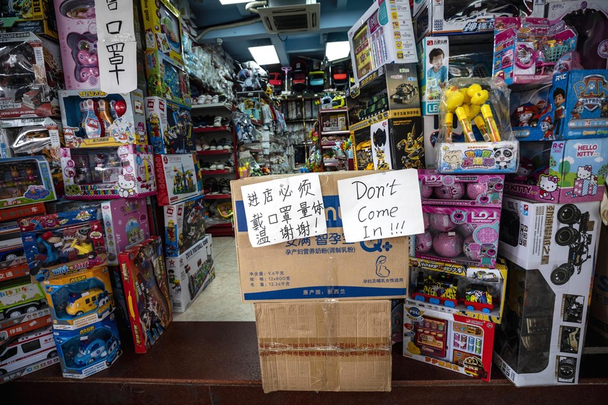 epa08360635 Sign in Chinese urging people to wear a mask when entering a shop stands next to sign in English ?Don?t come in!!!? in part of the town where most of the African people lives and works in  ...