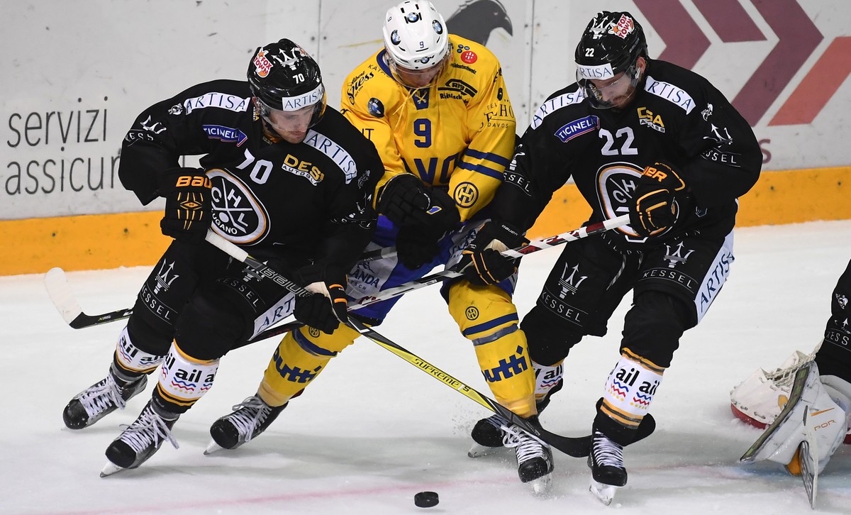 Lugano's player Matteo Romanenghi, Davos's player Tino Kessler and Lugano's player Stefan Ulmer, from left, fight for the puck, during the preliminary round game of National League Swis ...
