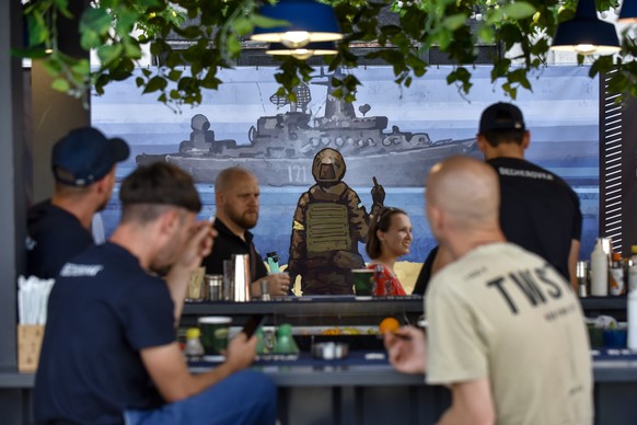 epa10035813 A poster with the iconic depiction of a Ukrainian soldier gesturing towards a Russian warship off Snake Island is seen in a bar in Kyiv (Kiev), Ukraine, 26 June 2022. Multiple airstrikes h ...