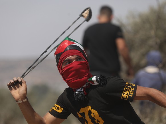 epa09401477 Palestinian protester uses his slingshot to hurl stones during a protest against Israeli settlements, on the lands of the West Bank city of Beita, 06 August 2021. One Palestinian was kille ...