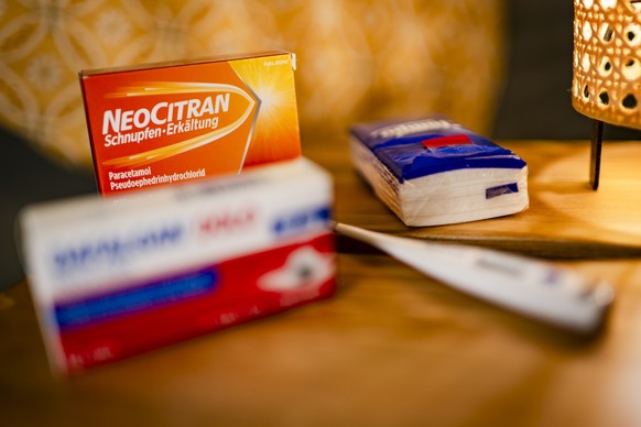 Une illustration sur le theme de la grippe montre une table de chevet devant un lit avec un medicament NeoCitran contre le Rhume et le Refroidissement (Schnupfen und Erkaeltung), une boite de Dafalgan ...