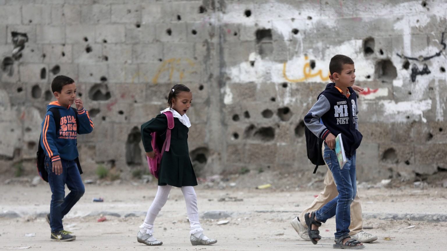 epa04735237 Palestinian children walk to their school along a destroyed wall, damaged during Israeli Hamas conflict of 2014, in Al Shejaeiya neighbourhood in the east of Gaza City on, 06 May 2015. EPA ...