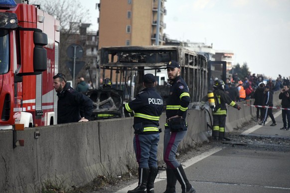 Firefighters and police officers stand by the gutted remains of a bus in San Donato Milanese, near Milan, Italy, March 21, 2019. Italian authorities say a bus driver transporting schoolchildren stoppe ...
