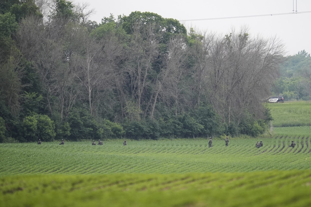 Members of law enforcement agencies search near a wooded area close to where a vehicle suspected to belong to shooting suspect, Vance Boelter, was found Sunday, June 15, 2025, in Belle Plaine, Minn. ( ...