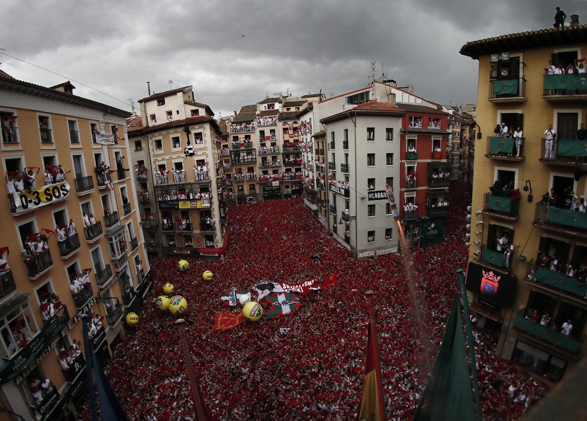 epa10054772 Revellers hold up the traditional red scarves at the Consistorial Square during the 'chupinazo' that marks the beginning of the San Fermin Festival in Pamplona, Navarra, Spain, 0 ...