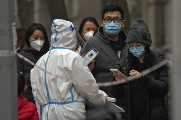FILE - A man shows his health check QR code as he and others line up to get their routine COVID-19 throat swabs at a coronavirus testing site in Beijing, Thursday, Nov. 24, 2022. (AP Photo/Andy Wong,  ...