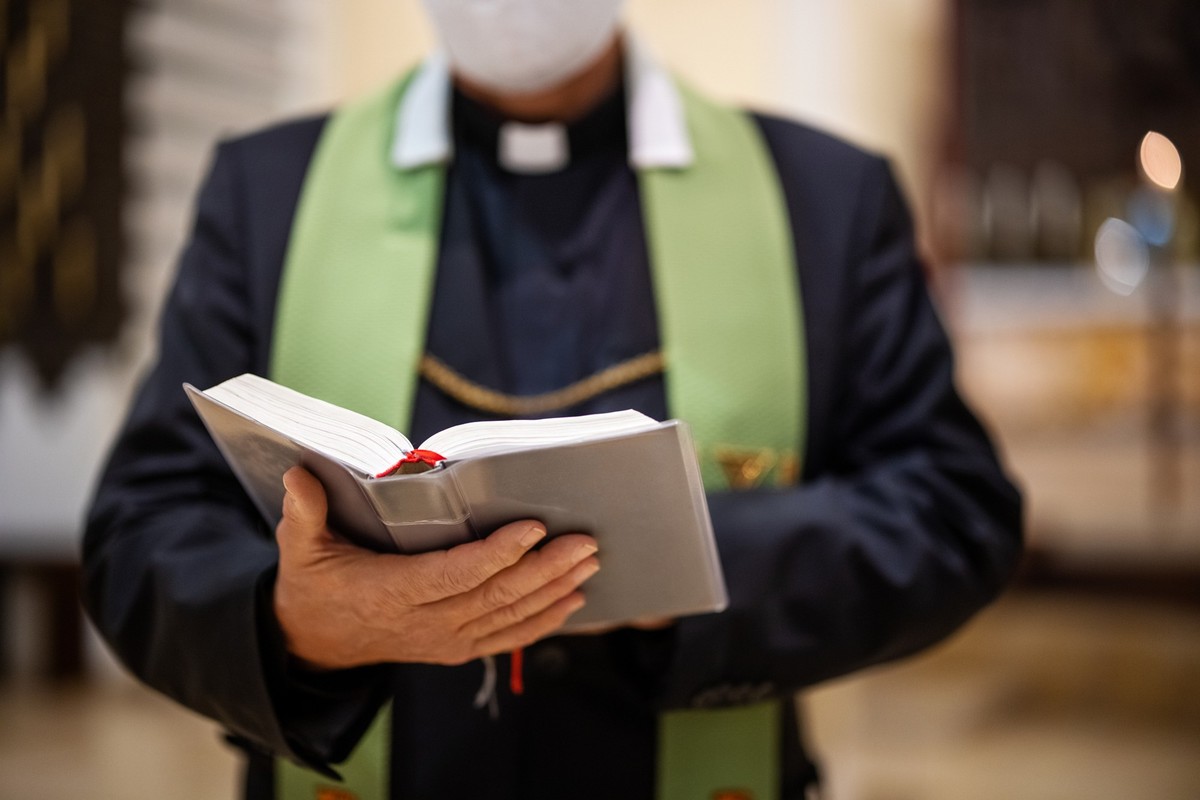 Close-up of a priest reading bible during congregation in church. Pastor reciting bible during a mass.