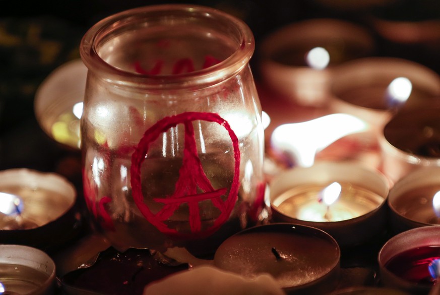 epa05027235 A candle with a piece sign in the shape of the Eiffel tower is seen at a memorial near the Bataclan concert venue in Paris, France, 15 November 2015. At least 132 people were killed in a s ...