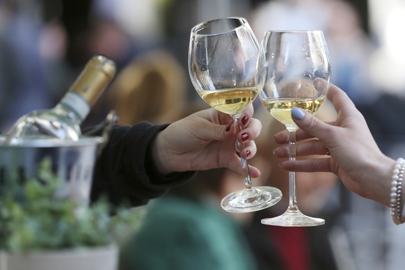 Women toast with white wine at a table in the outdoor area of a restaurant, in Duesseldorf, Germany, Friday, May 21, 2021. After months of forced break, restaurateurs in Duesseldorf are allowed to wel ...