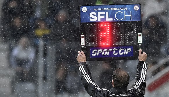 Der vierte Offizielle Schiedsrichter Lukas Faehndrich zeigt im stroemenden Regen die Nachspielzeit an, im Fussball Meisterschaftsspiel der Super League zwischen dem FC Thun und dem FC Basel, am Pfings ...