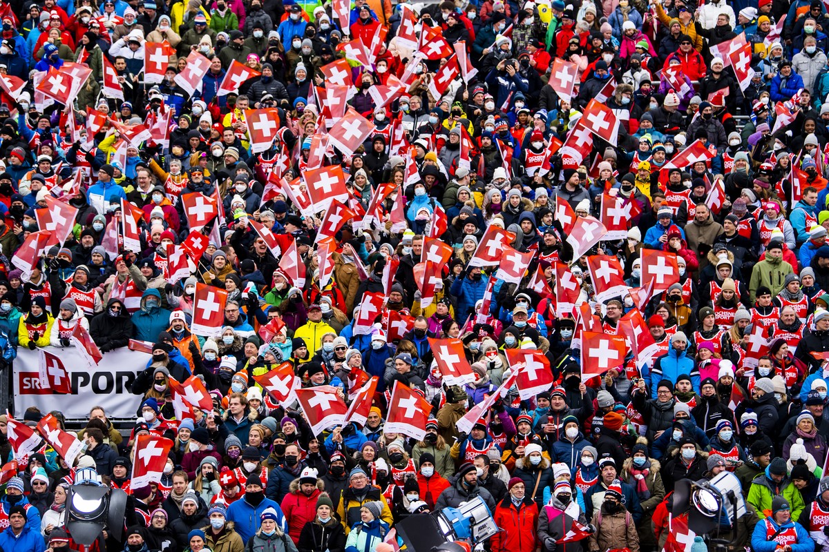 The spectators with or without protective masks stand in the finish area during the second run of the men's giant slalom race at the Alpine Skiing FIS Ski World Cup in Adelboden, Switzerland, Sat ...