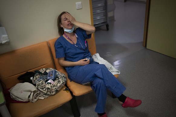 Nurse Marie-Laure Satta caresses her face during a pause in her New Year&#039;s Eve shift in the COVID-19 intensive care unit at the la Timone hospital in Marseille, southern France, Friday, Dec. 31,  ...