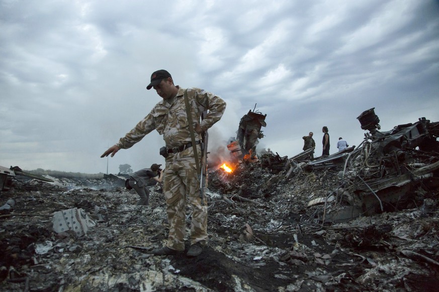 FILE- In this July 17, 2014, file photo, people walk amongst the debris at the crash site of MH17 passenger plane near the village of Grabovo, Ukraine, that left 298 people killed. A Dutch court on We ...