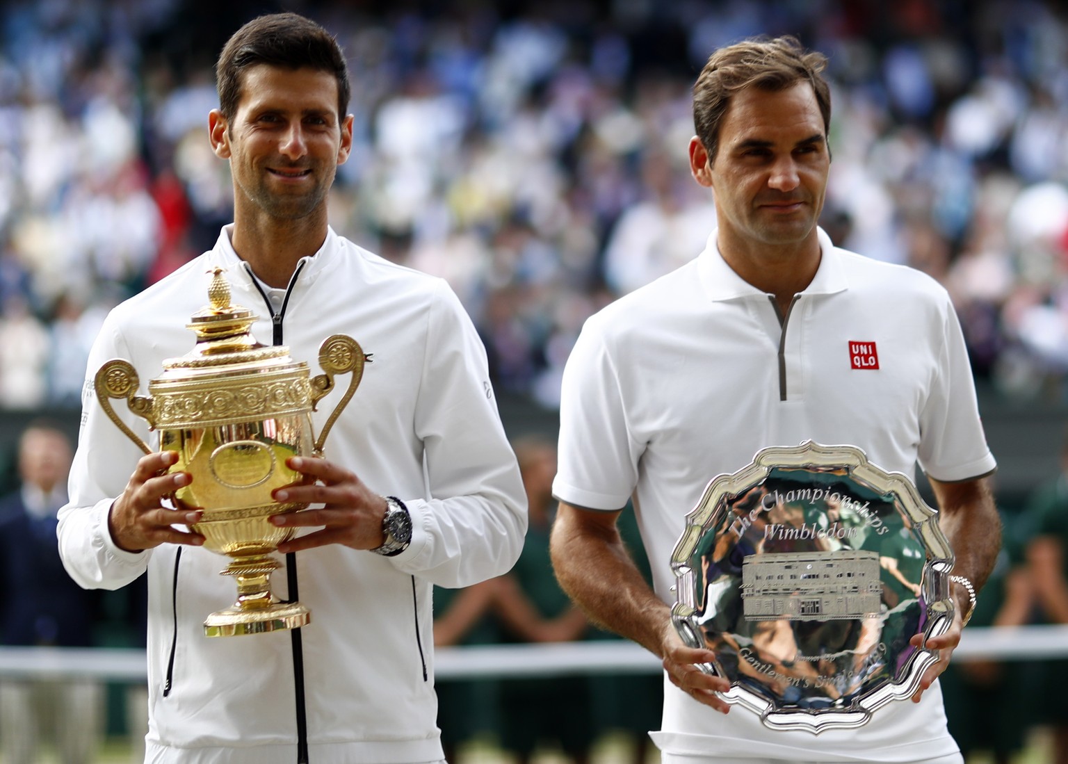 epa07717317 Novak Djokovic of Serbia (L) with the championship trophy after defeating Roger Federer of Switzerland (R) in the men&#039;s final of the Wimbledon Championships at the All England Lawn Te ...