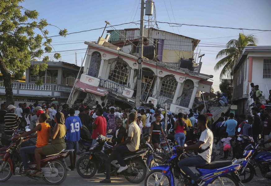 People gather outside the Petit Pas Hotel, destroyed by the earthquake in Les Cayes, Haiti, Saturday, Aug. 14, 2021. A 7.2 magnitude earthquake struck Haiti on Saturday, with the epicenter about 125 k ...