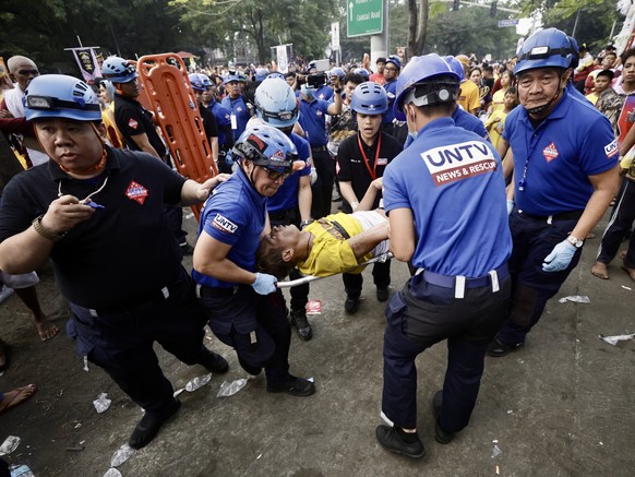 epa11813946 A Catholic devotee who was hurt in crowd of people jostling to get closer to the image of the Black Nazarene is carried by rescuers during the procession marking the feast day of the Black ...