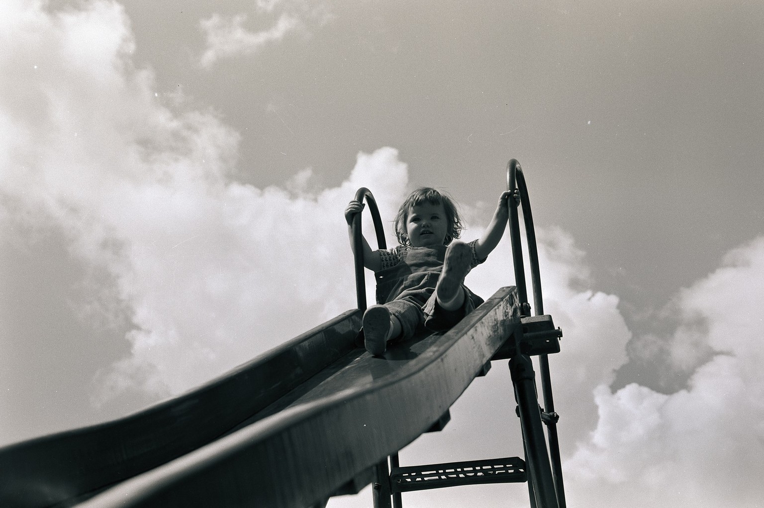 (Original Caption) Ready for a slide. A girl is shown poised at the top of a slide, ready for descent. Model: Susan McPeak. Ca. 1940s-1950s.
